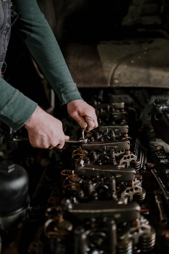 Close-up of a mechanics hands using tools to repair an engine. Indoor setting.